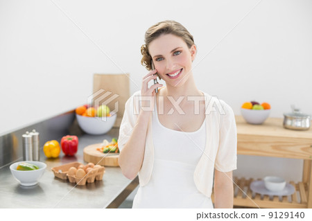Content young woman honing while standing in kitchen 9129140