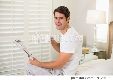 Smiling man with coffee cup reading newspaper Smiling man with coffee cup reading newspaper 9129198