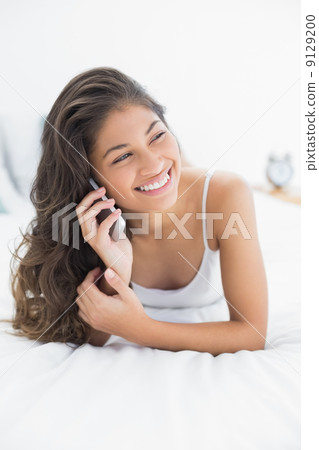 Cheerful woman using mobile phone in bed Cheerful woman using mobile phone in bed 9129200