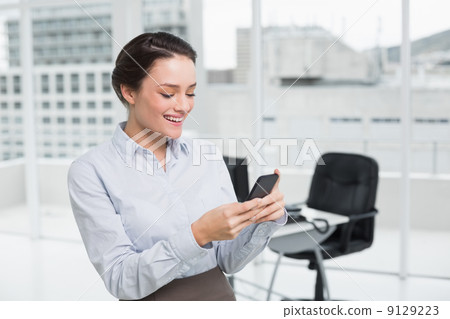 Smiling businesswoman reading text message in office 9129223