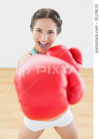 Beautiful playful woman in red boxing gloves at fitness studio 9129618