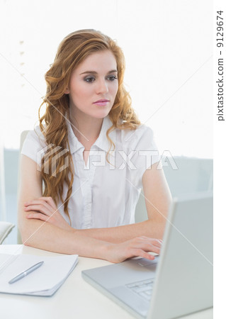 Serious businesswoman using laptop at office 9129674