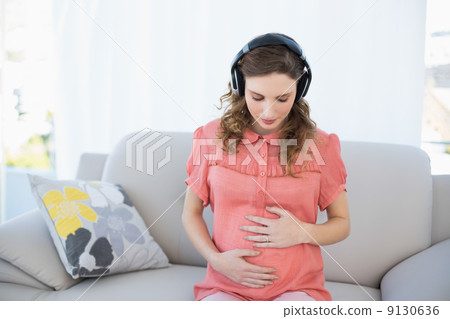 Beautiful calm pregnant woman relaxing listening to music in the Beautiful calm pregnant woman relaxing listening to music in the 9130636