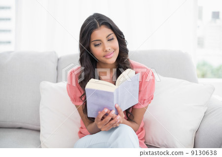 Calm cute brunette sitting on couch reading a book Calm cute brunette sitting on couch reading a book 9130638