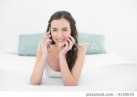 Relaxed young woman using mobile phone in bed Relaxed young woman using mobile phone in bed 9130639