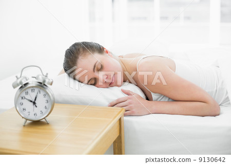 Woman sleeping in bed with focus on alarm clock Woman sleeping in bed with focus on alarm clock 9130642