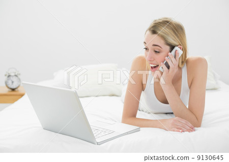 Astonished lovely woman phoning with her smartphone looking at h Astonished lovely woman phoning with her smartphone looking at h 9130645