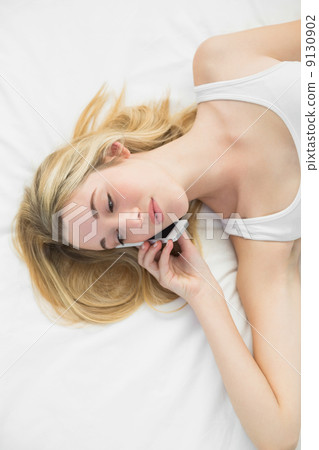 Chatting cute woman using her smartphone for phoning lying on he Chatting cute woman using her smartphone for phoning lying on he 9130902