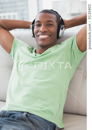 Relaxed Afro man with headphones sitting on sofa Relaxed Afro man with headphones sitting on sofa 9130905