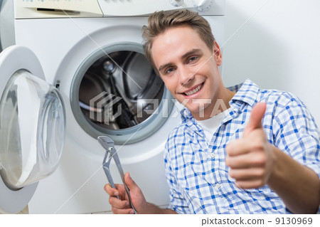 Technician repairing washing machine while gesturing thumbs up Technician repairing washing machine while gesturing thumbs up 9130969