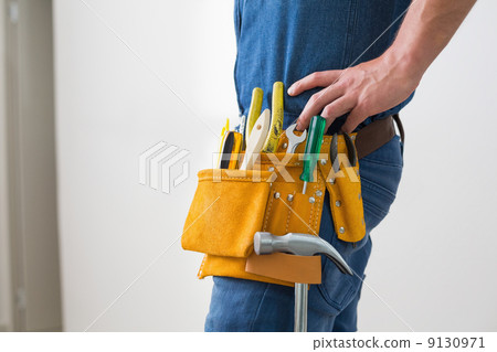 Mid section of handyman with toolbelt around his waist 9130971