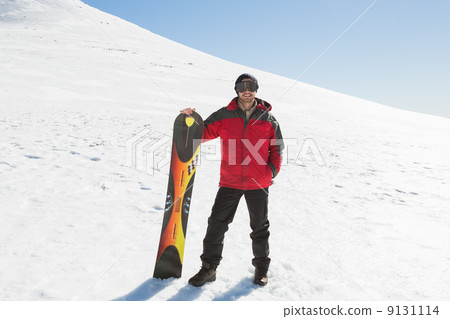 Smiling man with ski board standing on snow Smiling man with ski board standing on snow 9131114