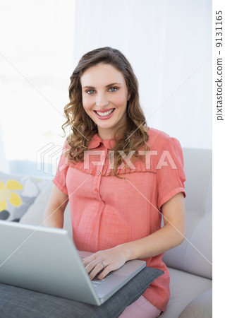 Beautiful pregnant woman working with her notebook sitting on a Beautiful pregnant woman working with her notebook sitting on a 9131165