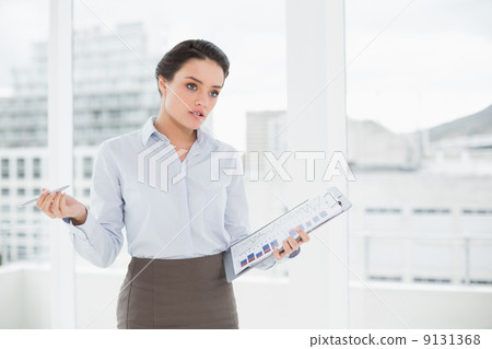 Elegant businesswoman with graphs in office Elegant businesswoman with graphs in office 9131368