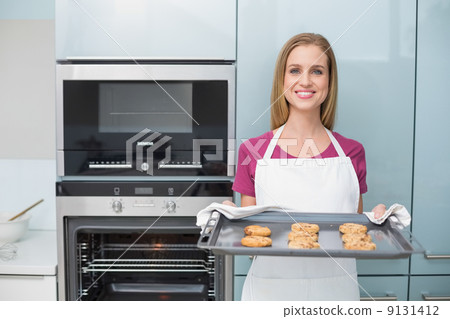 Casual attractive woman holding baking tray with cookies Casual attractive woman holding baking tray with cookies 9131412