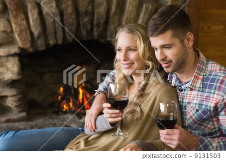 Couple with wineglasses in front of lit fireplace Couple with wineglasses in front of lit fireplace 9131503