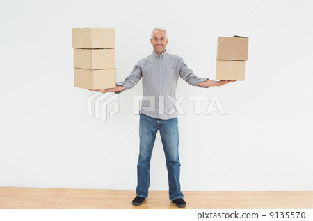 Smiling mature man carrying boxes in a new house 9135570