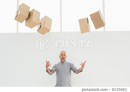 Annoyed mature man with falling boxes 9135661