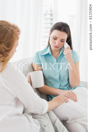Woman consoling a crying female friend at home 9135904