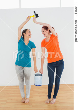 Cheerful friends with brushes and paint can in new house Cheerful friends with brushes and paint can in new house 9136839