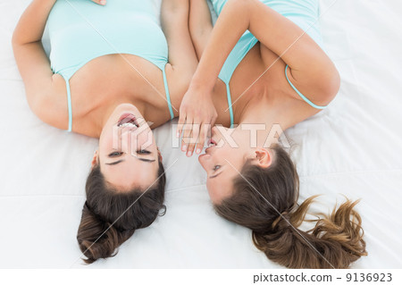 Two young female friends gossiping in bed 9136923
