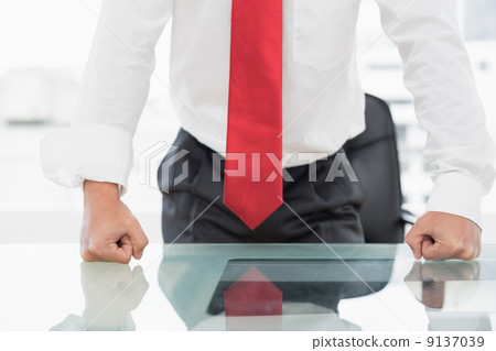 Mid section of a businessman with clenched fists on desk Mid section of a businessman with clenched fists on desk 9137039