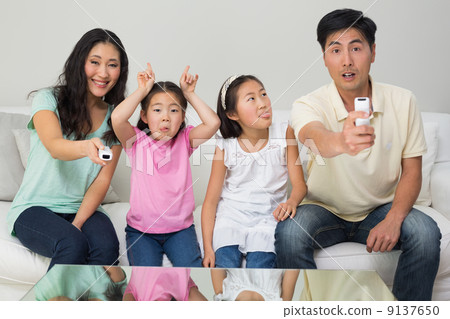 Family of four watching tv in living room Family of four watching tv in living room 9137650