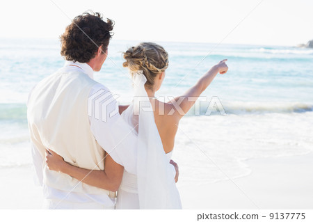 Newlyweds standing by the sea with wife pointing Newlyweds standing by the sea with wife pointing 9137775