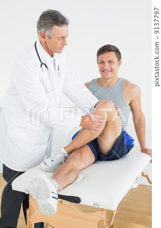 Portrait of a smiling young man getting his leg examined Portrait of a smiling young man getting his leg examined 9137797