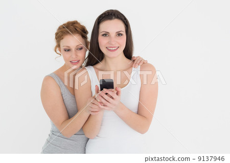 Two casual young female friends with mobile phone 9137946
