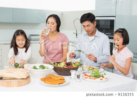 Young family of four enjoying healthy meal in kitchen Young family of four enjoying healthy meal in kitchen 9138355