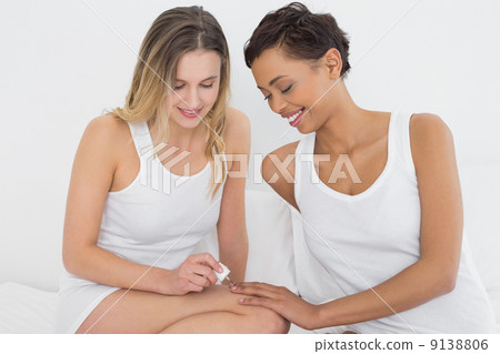 Pretty woman painting friends nails on bed Pretty woman painting friends nails on bed 9138806