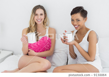Female friends with coffee cups in bed 9138864