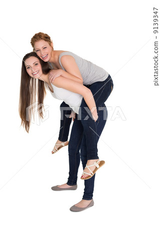 Full length portrait of a young female piggybacking friend Full length portrait of a young female piggybacking friend 9139347