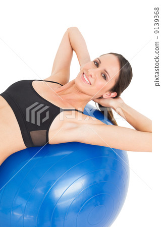 Portrait of a smiling fit woman stretching on fitness ball Portrait of a smiling fit woman stretching on fitness ball 9139368