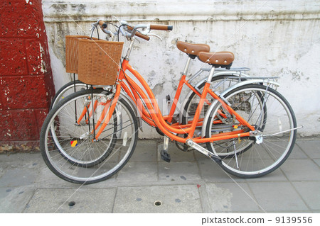 orange bicycle park near wall orange bicycle park near wall 9139556