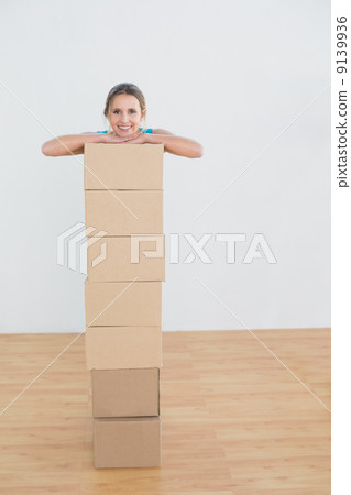 Woman moving in a new house with a stack of boxes Woman moving in a new house with a stack of boxes 9139936