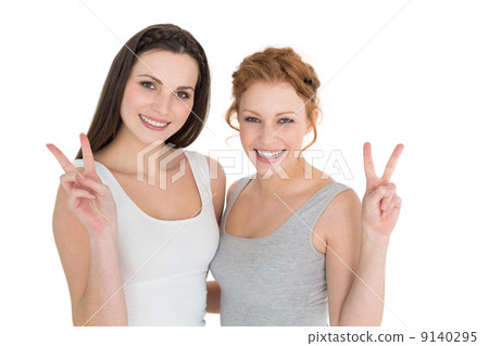 Portrait of two young female friends gesturing peace sign Portrait of two young female friends gesturing peace sign 9140295