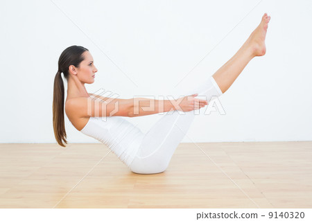 Toned woman doing the boat pose in fitness studio Toned woman doing the boat pose in fitness studio 9140320