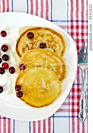 Flapjacks with cranberry in a plate on a napkin Flapjacks with cranberry in a plate on a napkin 9141822