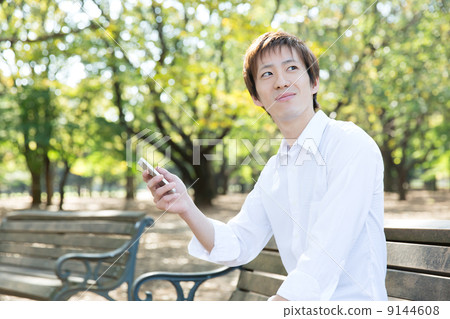 A man who uses a mobile phone in the park 9144608