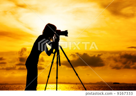 Silhouette female photographer at sunset 9167333