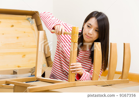 Asian woman using hammer for assembling chair Asian woman using hammer for assembling chair 9167356