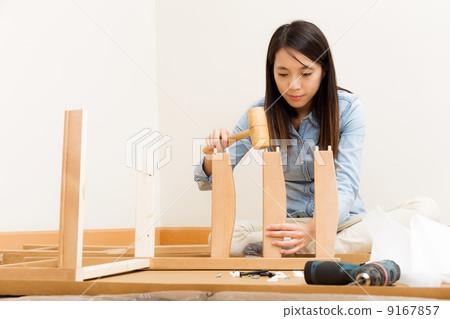 Asian woman using hammer for assembling chair Asian woman using hammer for assembling chair 9167857