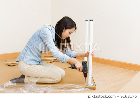 Asian woman using strew driver for assembling furniture Asian woman using strew driver for assembling furniture 9168176