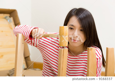 Asian woman using hammer for new furniture assembling Asian woman using hammer for new furniture assembling 9168337