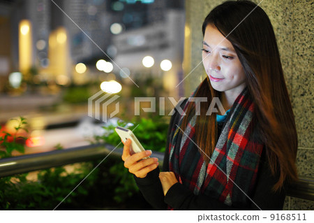 Woman using smartphone in city at night Woman using smartphone in city at night 9168511