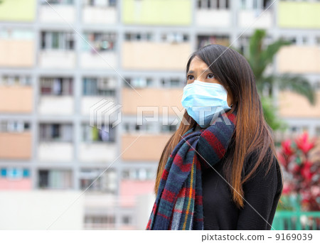 Woman wearing medical face mask in crowded city 9169039