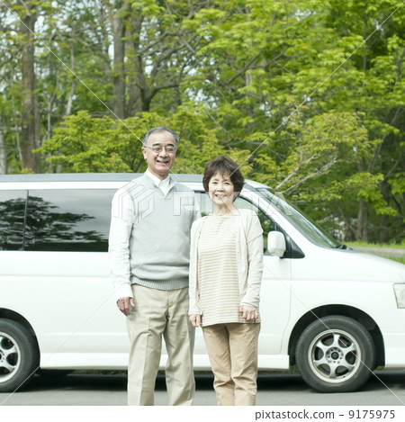 Senior couple smiling in front of car 9175975