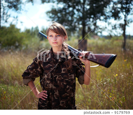 Young beautiful girl with a shotgun looks into the distance Young beautiful girl with a shotgun looks into the distance 9179769